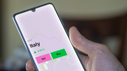 An investor's analizing the italy etf fund on a screen. A phone shows the prices of Italy