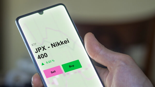 An investor's analizing the jpx - nikkei 400 etf fund on a screen. A phone shows the prices of JPX - Nikkei 400