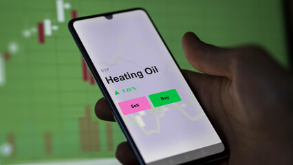 An investor's analizing the heating oil etf fund on a screen. A phone shows the prices of Heating Oil