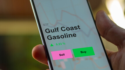 An investor's analizing the gulf coast gasoline etf fund on a screen. A phone shows the prices of Gulf Coast Gasoline