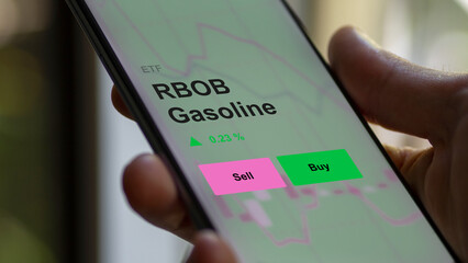 An investor's analizing the rbob gasoline etf fund on a screen. A phone shows the prices of RBOB Gasoline