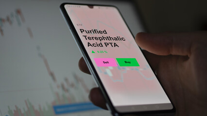 An investor's analizing the purified terephthalic acid pta etf fund on a screen. A phone shows the prices of Purified Terephthalic Acid PTA