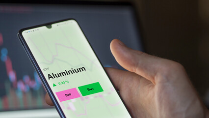 Aluminium fund, an investor's analizing the aluminium etf fund on a screen. A phone shows the prices of Aluminium