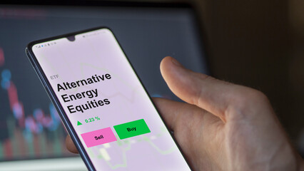 An investor's analizing the alternative energy equities etf fund on a screen. A phone shows the prices of Alternative Energy Equities