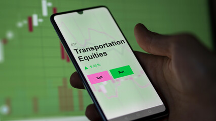 An investor's analyzing the transportation equities etf fund on a screen. A phone shows the prices of mobility equity ETF.