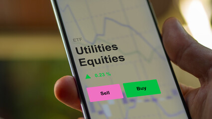 An investor's analizing the utilities equities etf fund on a screen. A phone shows the prices of Utilities Equities