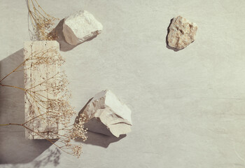 Flatlay minimal natural stone, marble or travertino surface background with stones and dry flowers....