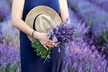 woman with straw hat and lavender bouquet in her hands in lavender field in summer. Travel, herbs, flowers concept