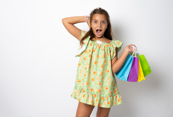 Sale. Cute little girl with many shopping bags on white background. Portrait of a kid on shopping....