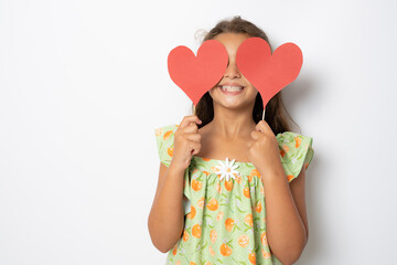 Happy girl with two carton paper small little heart figures standing isolated over white background. Love concept.