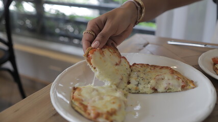 Chica joven toma porción de pizza vegana con verduras y salsa pesto en mesa blanca. Pizza sin...