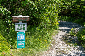 Fototapeta na wymiar A sign marking the trailhead to the ghost town of La Manche, Newfoundland is seen at the entrance to a forest.