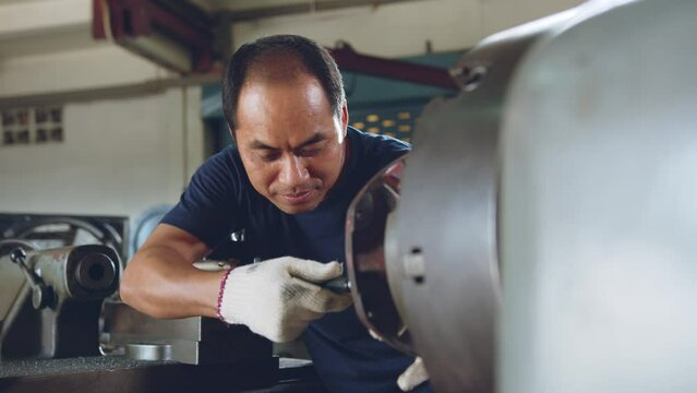 Technician asia worker using vernier caliper measure detail of workpiece for checking size in workshop lathe machine factory