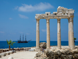 Ruins of the Temple of Apollo with pirate ship in old town of Side at beautiful summer day,...