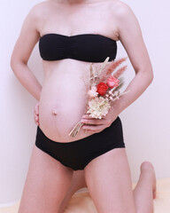 妊婦の身体とお腹の中の赤ちゃんと花束 - obrazy, fototapety, plakaty