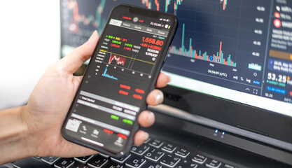 Female trader investor broker analyst holding a smartphone in hand analyzing stock market trading charts indexes data checking price using mobile