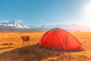 Bright red tourist tent in Altai mountains sunset, beautiful view nature. Concept travel hiking autumn