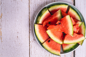 watermelon close up on fresh ripe juicy slices in a plate on wooden background copy space
