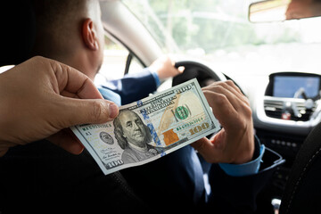 Passengers pay service fees to male taxi drivers. client pays for trip in dollars. 100 dollar bill in a male hand