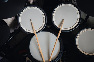 Top view of a electronic drum kit with cymbals and drums and a pair of wooden drumsticks, on a...