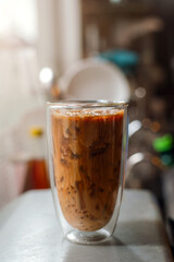 Ice coffee on a table with cream being poured into it showing the texture