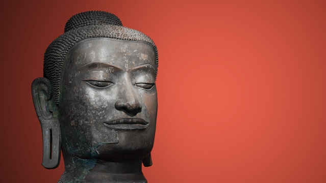 The head of an ancient Buddha statue was made of bronze. image on copy space red background.
