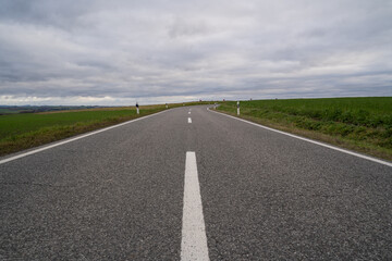 Country road with cloudy sky on a cold day in autumn 