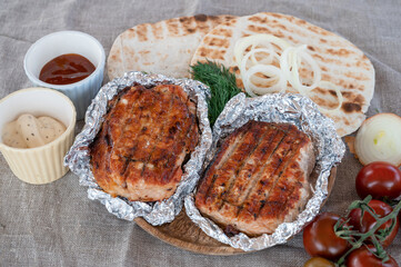Grilled pork meat in foil with flapjack and vegetables. Summer rest concept