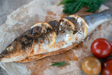Appetizing sibas fish with greens and vegetables. On a wooden background.