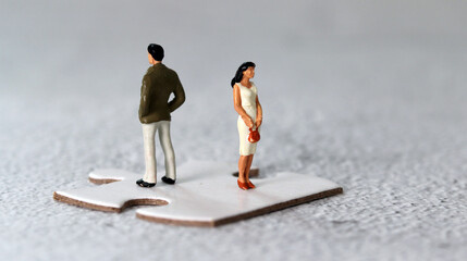 Miniature people standing on puzzle pieces. The concept of gender conflict.
