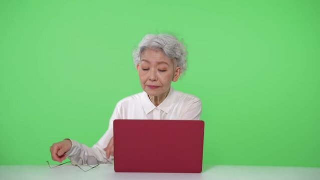 ノートパソコンを使うシニア女性　クロマキー合成用グリーンバック