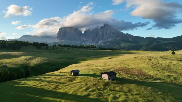 Aerial view of Seiser Alm plateau with traditional wooden mountain cottages on the meadows in Dolomites mountains in Italy . Morning drone shot of idyllic Alpe di Suisi blooming meadow in South Tyrol.