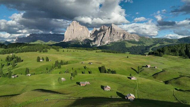 Aerial view of Seiser Alm plateau with traditional wooden mountain cottages on the meadows in Dolomites mountains in Italy . Morning drone shot of idyllic Alpe di Suisi blooming meadow in South Tyrol.