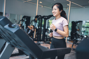 Fototapeta na wymiar Happy Asian woman running on a treadmill in the gym.Healthy lifestyle concept.