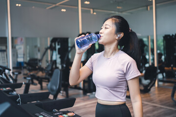 Portrait asian beautiful sport woman wearing sportwear on treadmill machine , she drinking water.