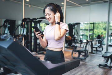 Young woman exercising on a treadmill and listening to music in the gym with copy space