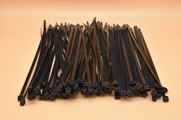 Black cable ties isolated on orange background. Plastic Tie Wraps.