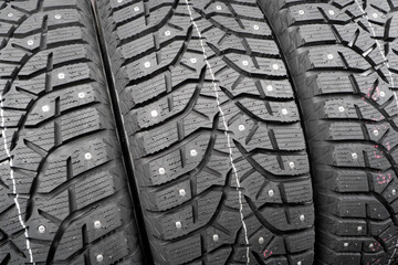 Winter studded tire. Winter car tires background. Tire stack background. Tyre protector close up....