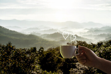 Man holding hot coffee cup forest and mountain backdrop foggy morning heart-shaped steam