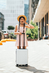 Portrait of young woman with suitcase and looking at camera - 518031086