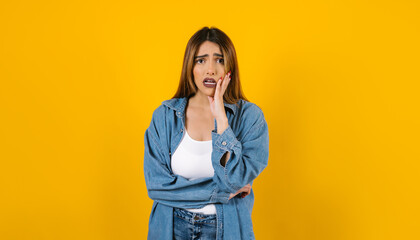 portrait of brunette young hispanic woman frustrated, worried or bored with copy space on yellow background in Mexico Latin America	
