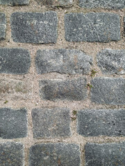 Texture of old dark gray granite paving stones, top view. Background from natural block stone.