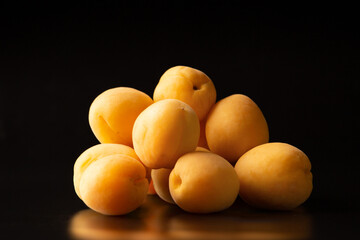 A handful of ripe raw apricots on a dark background
