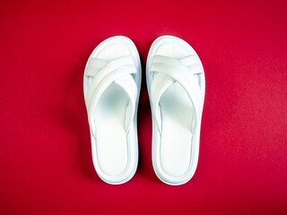 Women's summer white slippers on a red background. Slippers. Horizontal image