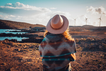Back view of woman admiring landscape with windmills turbines in background. Concept of travel and...