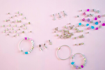 Multicolored beads for making jewelry on a pink background. Beautiful bracelet with metal plastic beads, the concept of homemade jewelry.