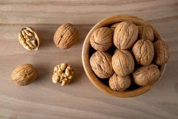 Bowl of walnuts and whole walnut kernels on wooden background,top view