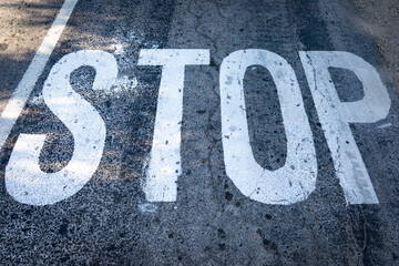Palabra "STOP" pintada en el suelo de una carretera (textura, alquitrán, asfalto)