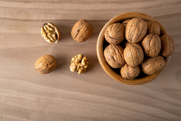 Bowl of walnuts and whole walnut kernels on wooden background,top view