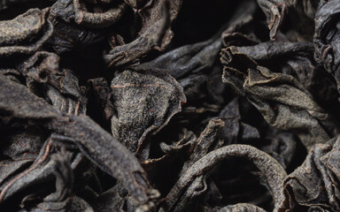 Dried black tea leaves as background.